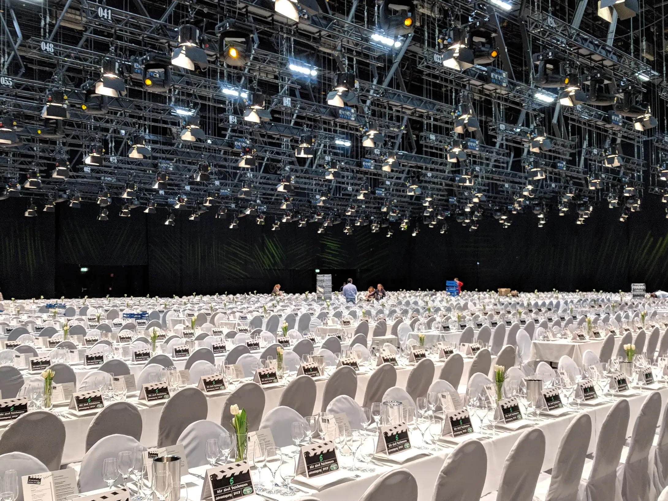 Große Veranstaltungsfläche der Messe Essen mit festlich eingedeckten Tischen, weißen Stühlen und umfangreicher Lichttechnik an der Decke.