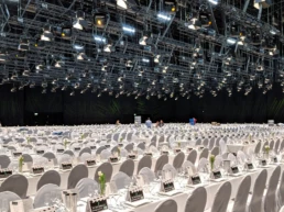 Große Veranstaltungsfläche der Messe Essen mit festlich eingedeckten Tischen, weißen Stühlen und umfangreicher Lichttechnik an der Decke.