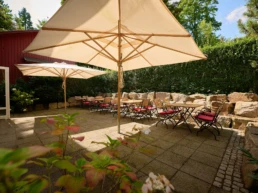 Terrasse im Parkhaus Hügel in Essen mit Sitzplätzen, Sonnenschirmen und grüner Umgebung