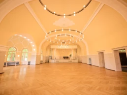 Großer Veranstaltungssaal im Stadtgarten Steele in Essen mit Parkettboden, Bühne und moderner Ringbeleuchtung