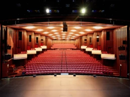 Großer Veranstaltungssaal in der Stadthalle Mülheim mit Bühne und roter Reihenbestuhlung