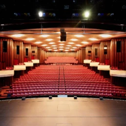 Gro&szlig;er Veranstaltungssaal in der Stadthalle M&uuml;lheim mit B&uuml;hne und roter Reihenbestuhlung