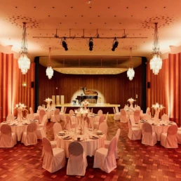 Festlich eingedeckter Veranstaltungssaal in der Stadthalle M&uuml;lheim mit B&uuml;hne und Fl&uuml;gel