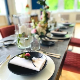 Festlich gedeckter Tisch mit Serviette, Blumendekoration und Gl&auml;sern