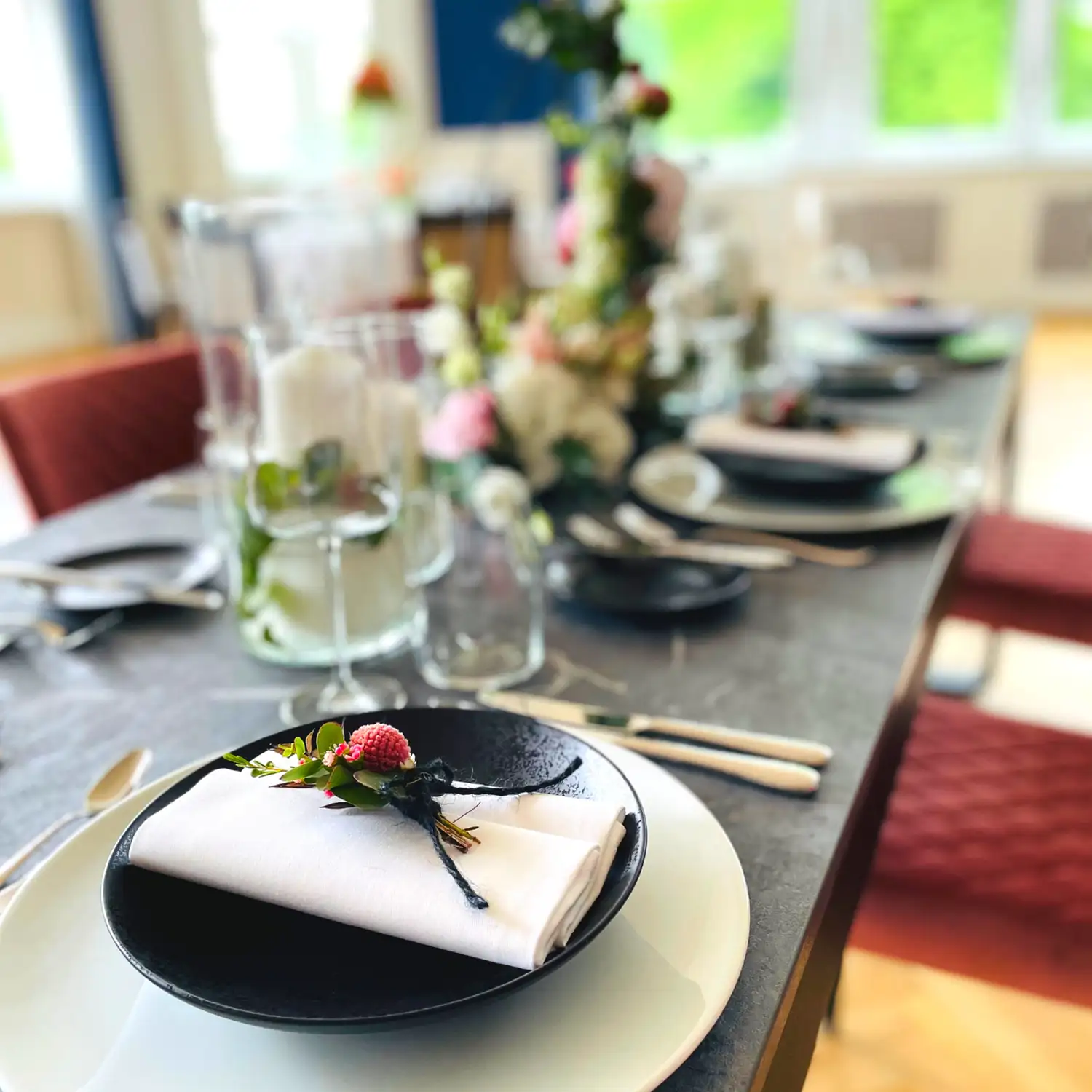 Festlich gedeckter Tisch mit Serviette, Blumendekoration und Gläsern