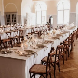 Festlich gedeckte Hochzeitstafel mit Kerzen, Blumendekoration und Holzst&uuml;hlen